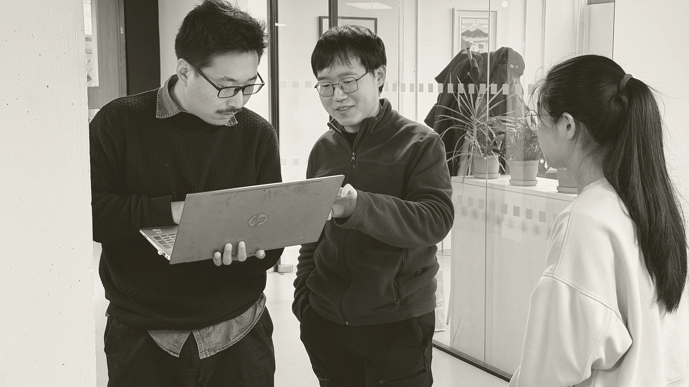 Three members of the Narrative team talking through work on a laptop in the office.